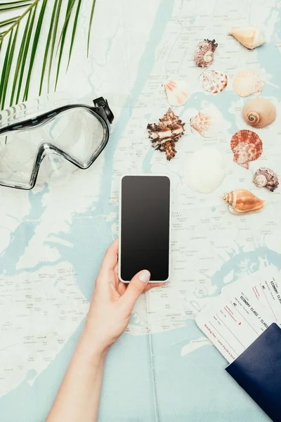 Обрізаний знімок жінки зі смартфоном і квитки на літак на карті подорожей — стокове фото
