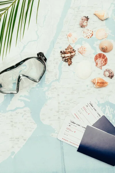 Vista superior de la máscara de buceo con conchas marinas y billetes de avión en el mapa de viajes - foto de stock