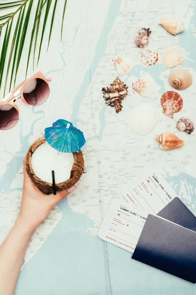 Cropped shot of woman with coconut cocktail and flight tickets on travel map — Stock Photo