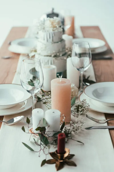 Nahaufnahme der stilvollen Tischdekoration mit Kerzen, leeren Gläsern und Tellern für die rustikale Hochzeit — Stockfoto