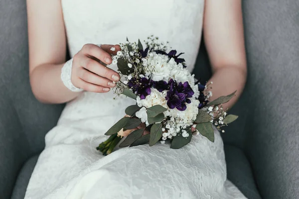 Partial view of bride in white dress with beautiful bridal bouquet resting in armchair — Stock Photo