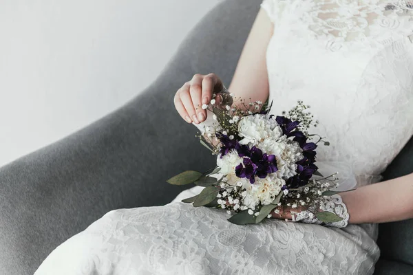 Partial view of bride in white dress with beautiful bridal bouquet resting in armchair — Stock Photo