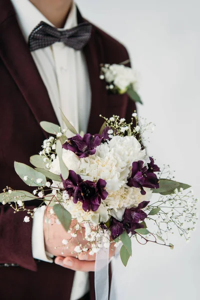 Частковий вид на нареченого в костюмі з красивим весільним букетом в руках — стокове фото