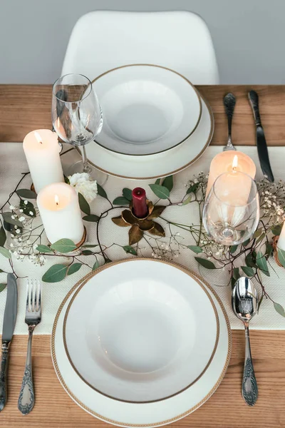 Close up view of stylish table setting with candles, empty wineglasses and plates for rustic wedding — Stock Photo