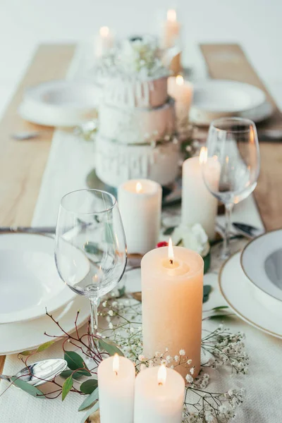 Nahaufnahme der stilvollen Tischdekoration mit Kerzen, leeren Gläsern und Tellern für die rustikale Hochzeit — Stockfoto