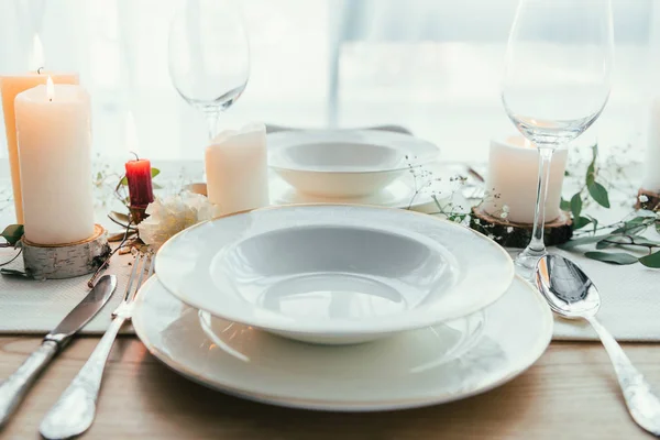 Close up view of stylish table setting with candles, empty wineglasses and plates for rustic wedding — Stock Photo