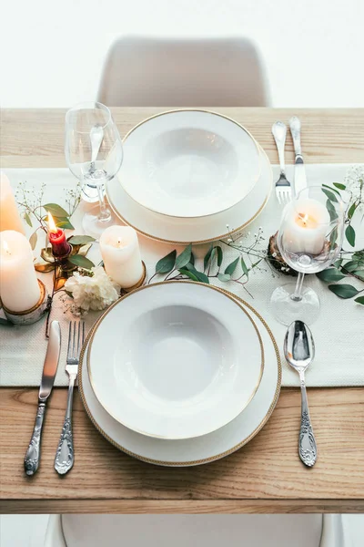 Vista de perto do cenário de mesa elegante com velas, copos de vinho vazios e pratos para casamento rústico — Fotografia de Stock