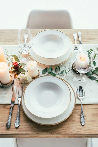 Close up view of stylish table setting with candles, empty wineglasses and plates for rustic wedding — Stock Photo