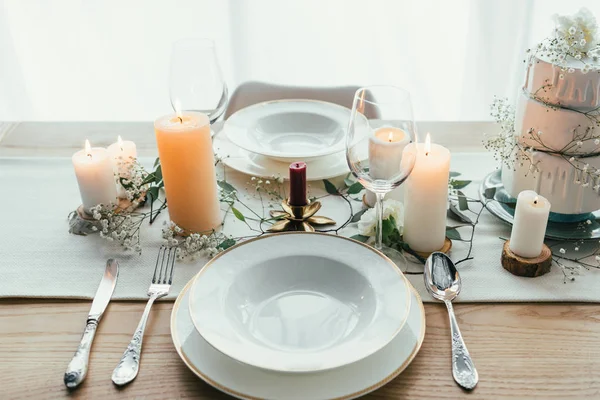 Vue rapprochée du décor élégant de la table avec des bougies, des verres à vin et un gâteau de mariage pour mariage rustique — Photo de stock