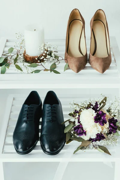 Vue rapprochée des chaussures de mariée et de marié, bougie et bouquet de mariage sur fond gris — Photo de stock