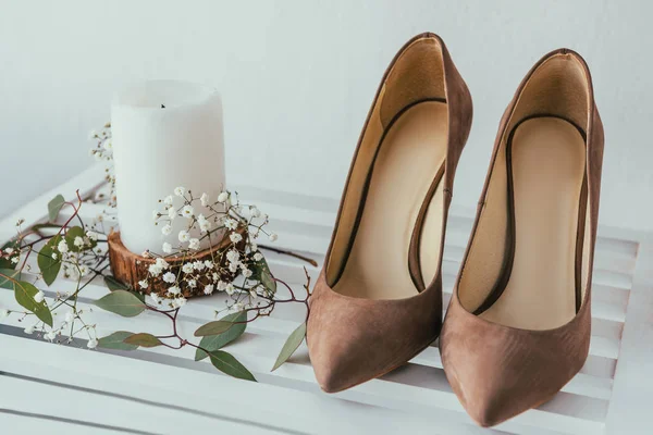 Vue rapprochée des chaussures de mariée, bougie et fleurs sur fond gris — Photo de stock