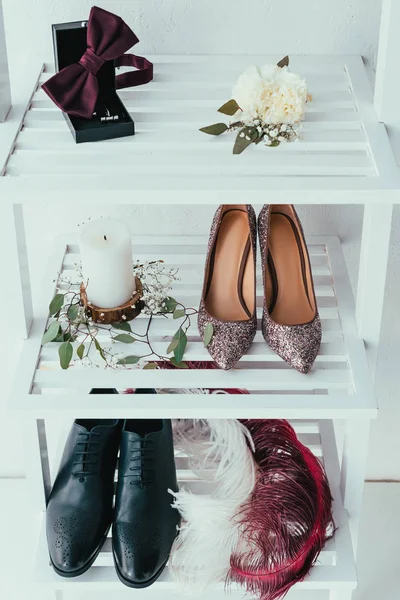 Vue rapprochée des chaussures de mariée et de marié, des bougies et des plumes décoratives sur fond gris — Photo de stock