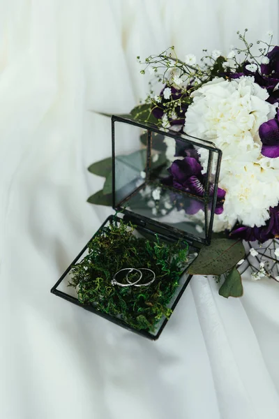 Vista de cerca de los anillos de boda en caja rústica y hermoso ramo de novia en lino blanco - foto de stock