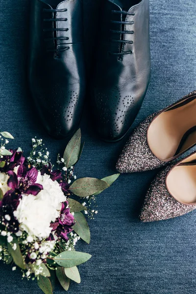 Vista superior de los zapatos arreglados de ramo de bodas, novias y novios sobre fondo azul - foto de stock