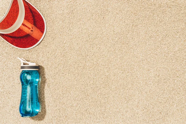 Draufsicht auf rote Kappe und Wasserflasche auf Sand — Stockfoto