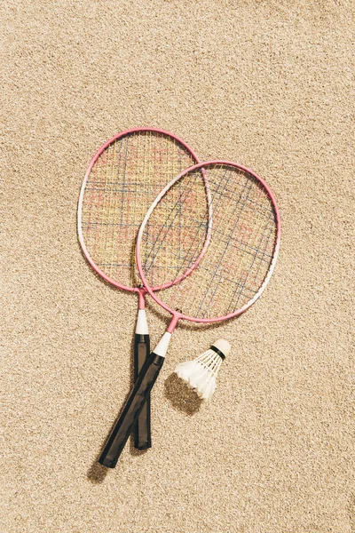 Top view of arranged badminton rackets and shuttlecock on sand — Stock Photo