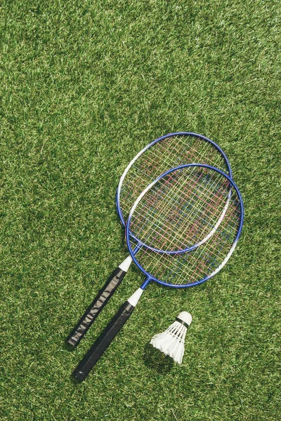 Top view of badminton rackets and shuttlecock on green grass — Stock Photo