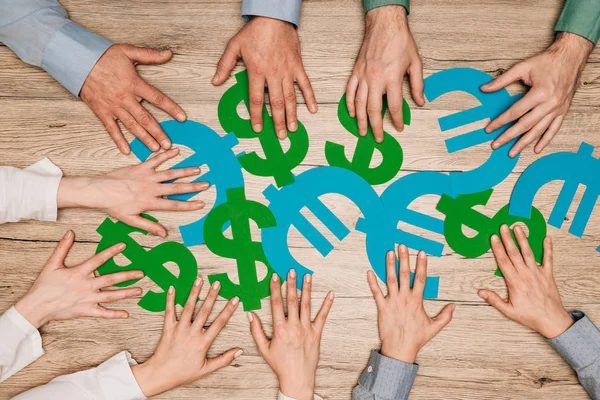 Top view of businesspeople with dollar and euro signs on wooden table — Stock Photo