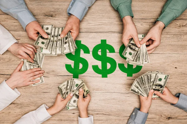 Top view of business partners counting dollar banknotes with dollar signs on wooden table — Stock Photo