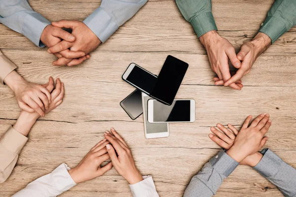 Top view of businesspeople at table with smartphones, cropped view — Stock Photo