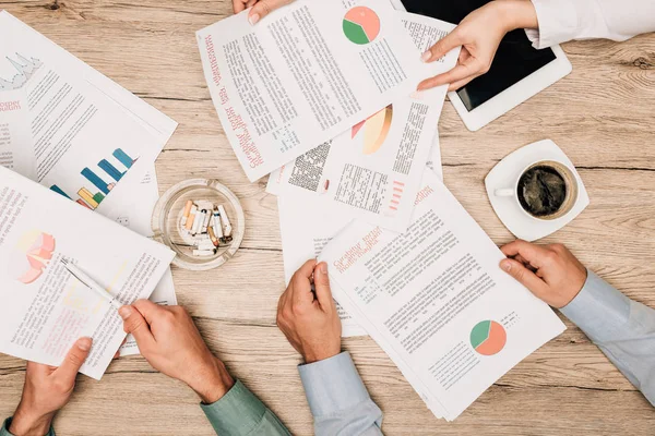 Top view of business partners with documents, digital tablet and ashtray on table — Stock Photo