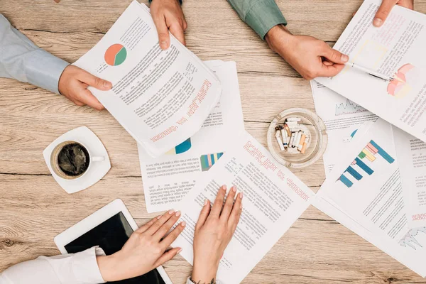 Top view of businesspeople working with documents by digital tablet and ashtray on table — Stock Photo