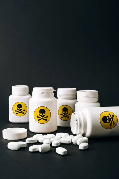 Flaschen mit Giftzeichen und Tabletten isoliert auf schwarz — Stockfoto