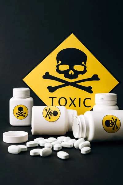 Токсичний знак з баночками та таблетками ізольовано на чорному — стокове фото