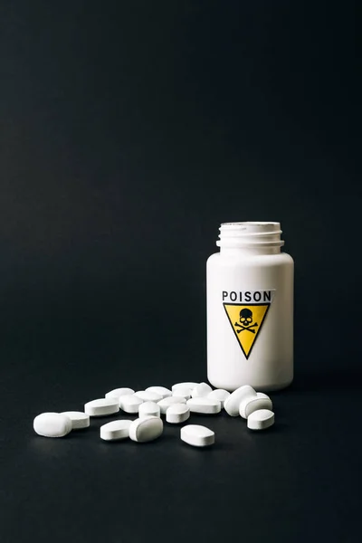 Bottle with poison sign and pills isolated on black — Stock Photo