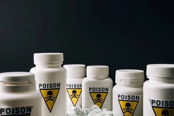 Selective focus of jars with poison sign and pills isolated on black — Stock Photo