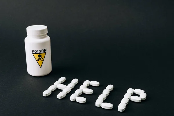 Pot avec signe empoisonné avec lettrage d'aide à partir de pilules isolées sur noir — Photo de stock
