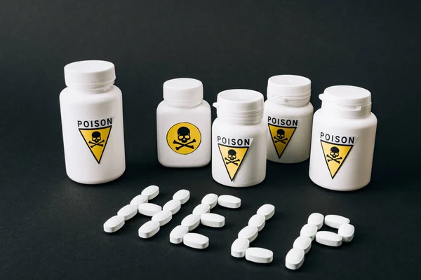 Jars with poison sign and help lettering from pills isolated on black — Stock Photo