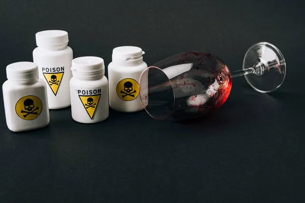 Weinglas mit Blut und Gläser mit Giftzeichen isoliert auf schwarz — Stockfoto