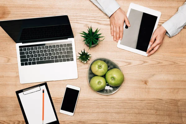 Vue du dessus de l'homme d'affaires utilisant la tablette numérique par smartphone et ordinateur portable sur la table, vue recadrée — Photo de stock