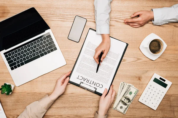 Top view of colleagues sign contract by laptop, money and calculator on table — Stock Photo