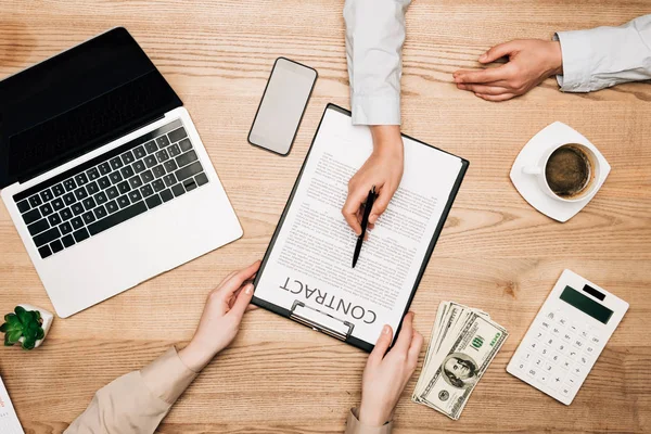 Kollegen unterschreiben Vertrag per Laptop, Geld und Taschenrechner auf dem Tisch — Stockfoto