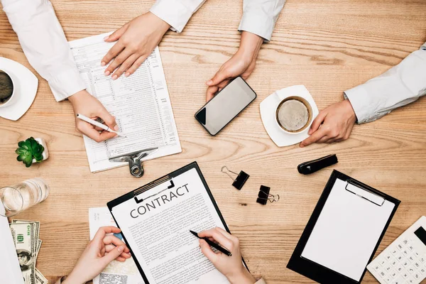 Вид зверху на бізнес-партнерів з контрактом, папером і кавою на дерев'яному столі — стокове фото