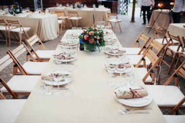 Kiev / Ukrayna - 09 / 02 / 2017 Düğün Süslemeleri. Kırsal Düğün Masası Ayarlama. Tabak, çatal, gözlük, bıçak, bej kumaş masa örtüsü, tahta sandalyeler. Masanın ortasında çiçeklerle süslenmiş..