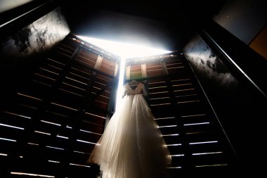 Kiev / Ukrayna - 06 / 22 / 2008 - Ahşap kapıda asılı şık bir gelinlik ışığın içinden geçtiği