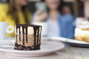 bir plaka üzerinde çikolatalı pasta / kek, görünümü bir tabakta - arka planda iki kız kadar yakın bir