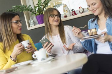 söz/üç arkadaş oldukları sırada üç yetişkin gülümseyen kız portresi konuşmak kurabiye ve kahve en sevdiğiniz kafe ve izleme olayları için sosyal ağlar üzerinde