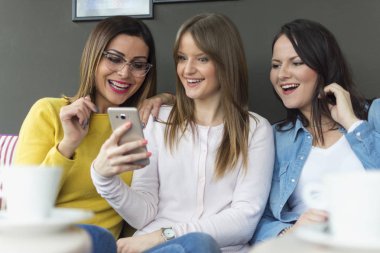 Yetişkin bir kız arkadaşları onun yeni erkek arkadaşı bir smartphone/a güzel gülümseyen kız fotoğrafı yeni erkek arkadaşı bir fotoğrafını arkadaşlarına gösterir