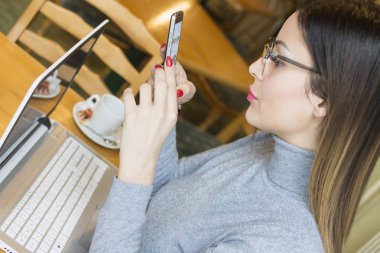 onun favori kafeteryada bir mola iken bir cep telefonu kullanarak iş kadını