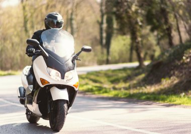 Şehir dışında bir yolculuğa bir motosiklet scooter olgun bir erkek rides