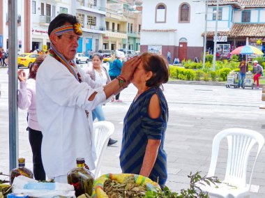 Cuenca, Ecuador - October 30, 2019: Unidentified indigenous healer (shaman) performing traditional for Ecuador ceremony of health purification using natural objects as stones, plants, seeds and others