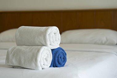 Otel yatak odasında yatağın üzerinde beyaz havlu sar