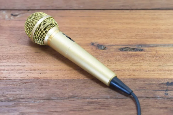 Gold microphone on wooden table.