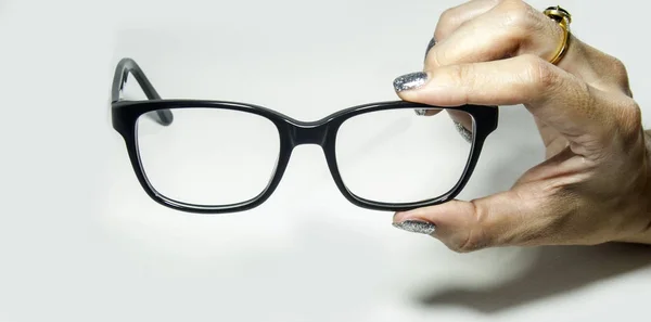 Mão segurando um óculos quadrados pretos. Fundo branco — Fotografia de Stock