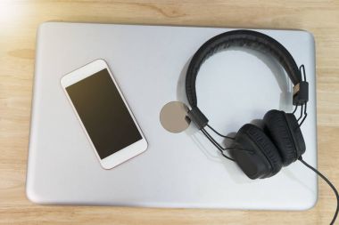 Kulaklık ve akıllı telefon üstünde laptop yerleştirilir. Kavramı relax