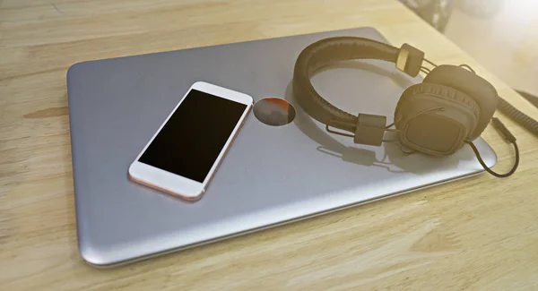 Słuchawki i inteligentny telefon jest umieszczony na laptopie. Koncepcja relaks — Zdjęcie stockowe